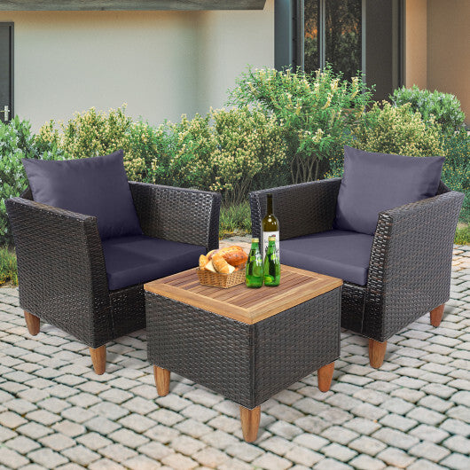 Two wicker chairs with dark cushions and a small wooden table on a patio.

